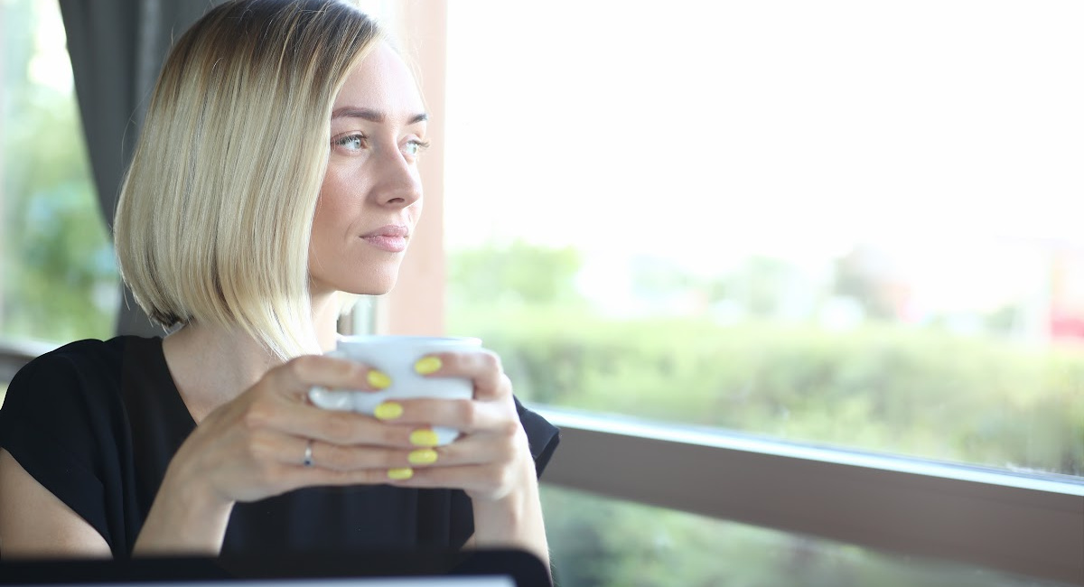 woman by a window sipping tea