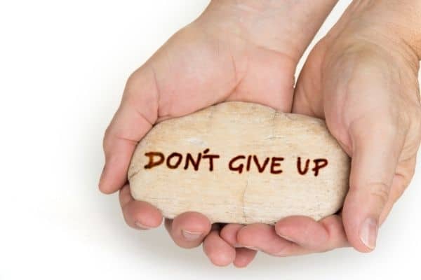 hand holding rock that says don't give up-finding an online therapist