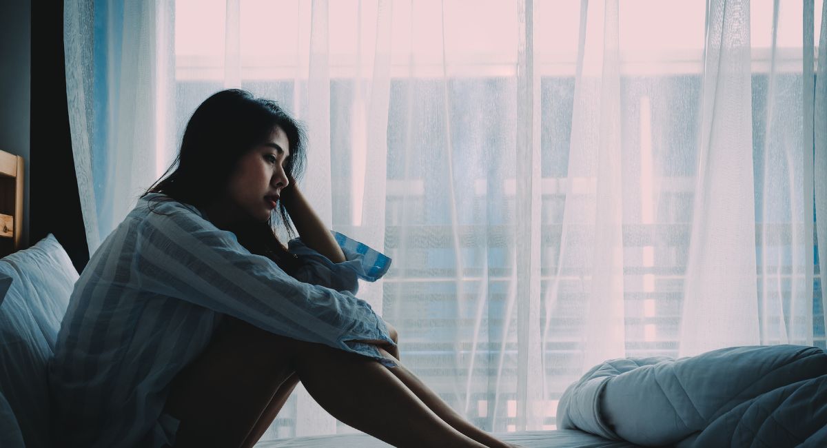 sad woman sitting on bed-why do women stay in abusive relationships article