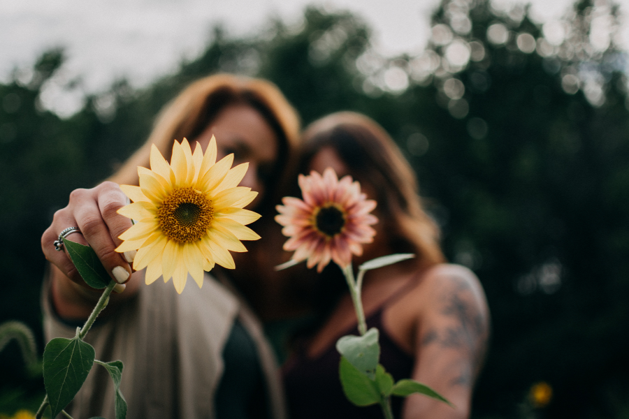 Two friends holding out flowers