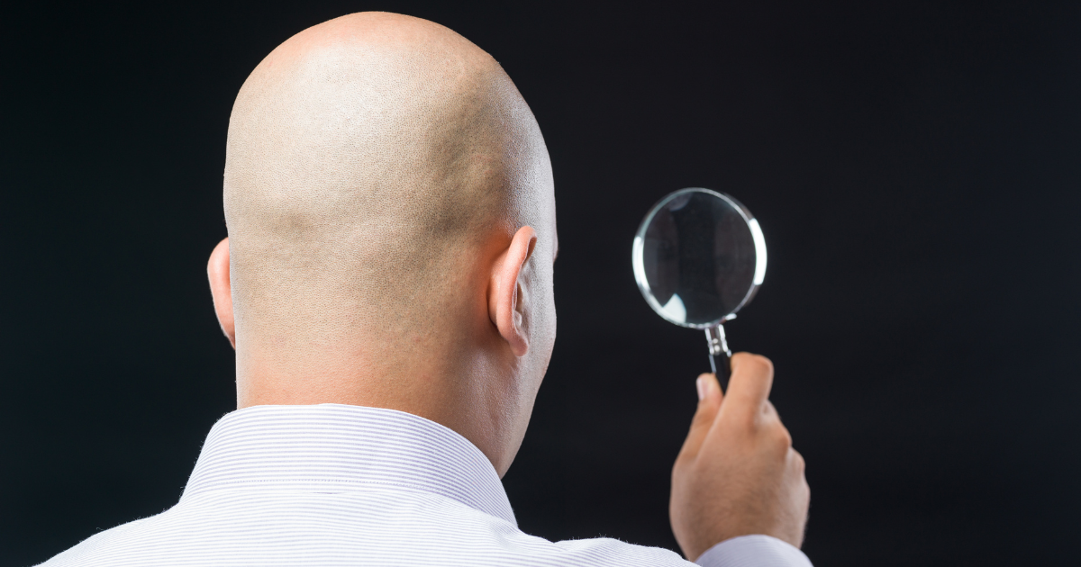 A bald man looking through a magnifying glass