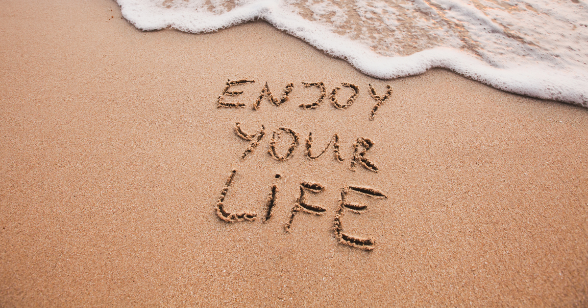 A writing on the beauch "enjoy your lfe" #JoyfulQuotes #RadiantLiving