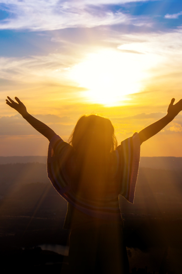 A woman facing the sun with open arms #MentalToughness #StrongMind