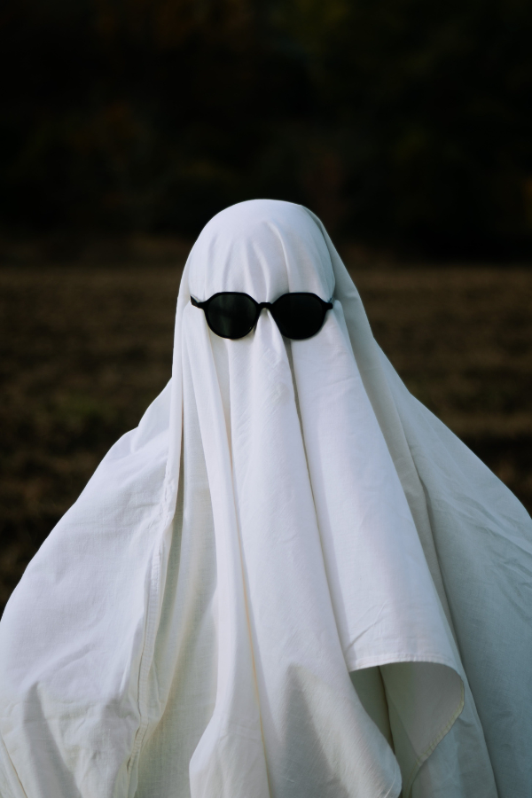 A person dressed as a ghost while wearing sunglasses #HalloweenParty #HalloweenThemes