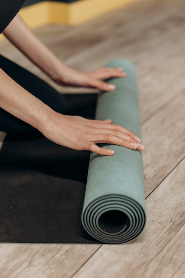 A woman rolling her yoga mat #MoveYourBody #MyBodyIsMyTemple