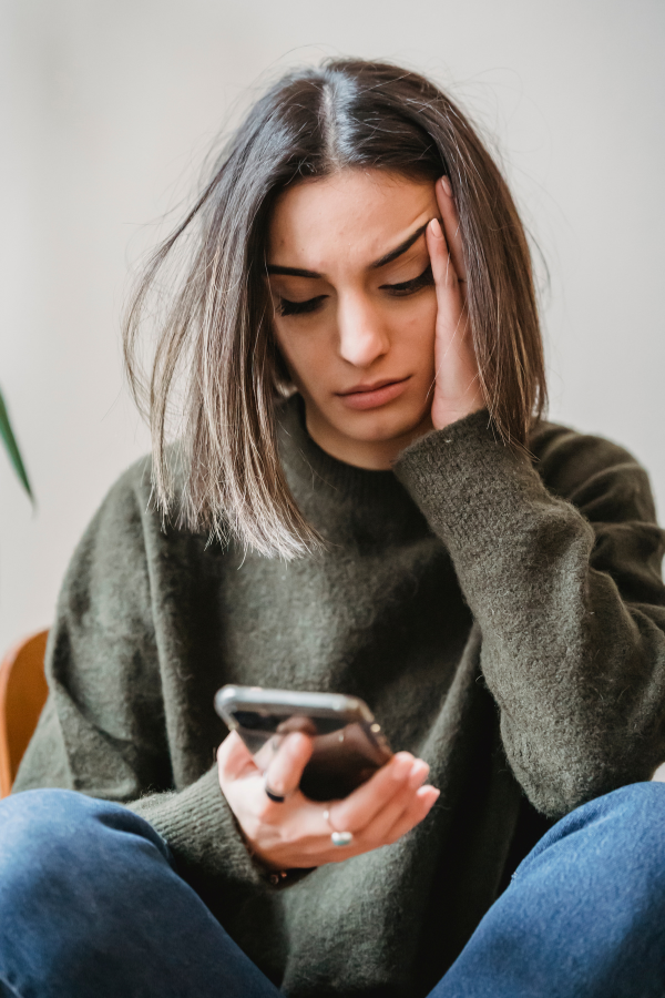 A woman with a worried expression looking at her phone #LoveOrInfatuation #InfatuationVsLove