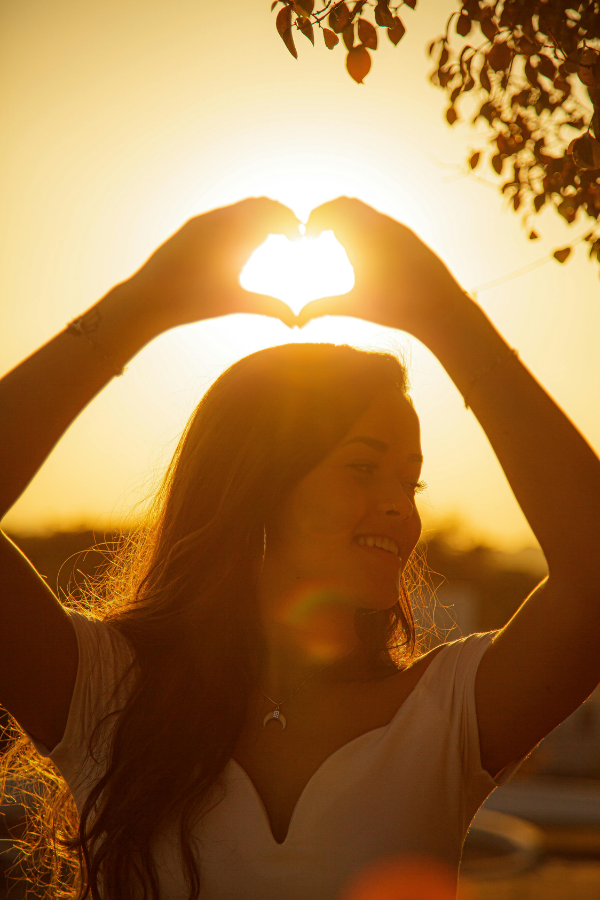 A woman holding up a heart symbol