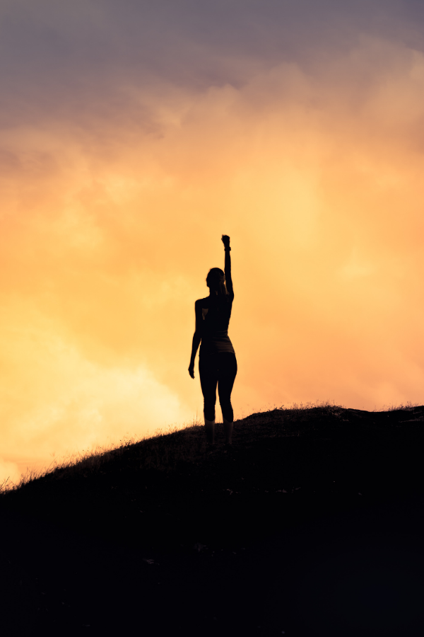 A strong woman standing on top of a mountain