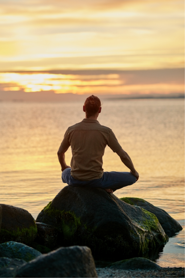 A woman meditating by the ocean