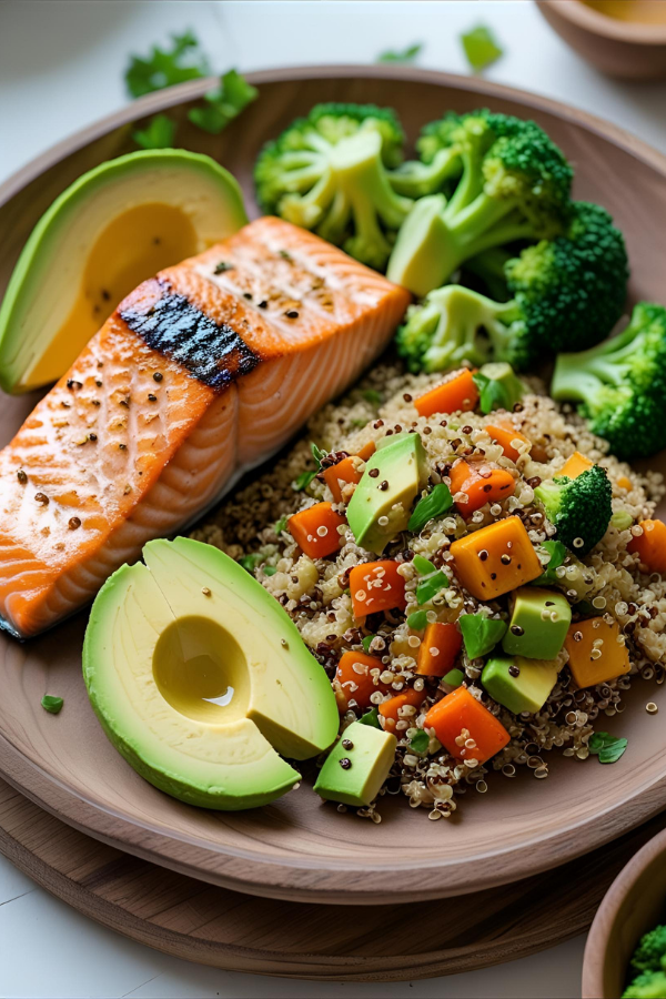 Healthy meal with grilled salmon, avocado, quinoa, and colorful vegetables on a wooden plate