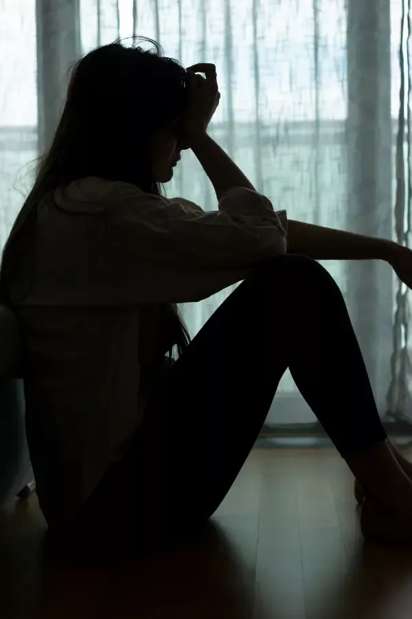 A sad woman sitting by the window sill