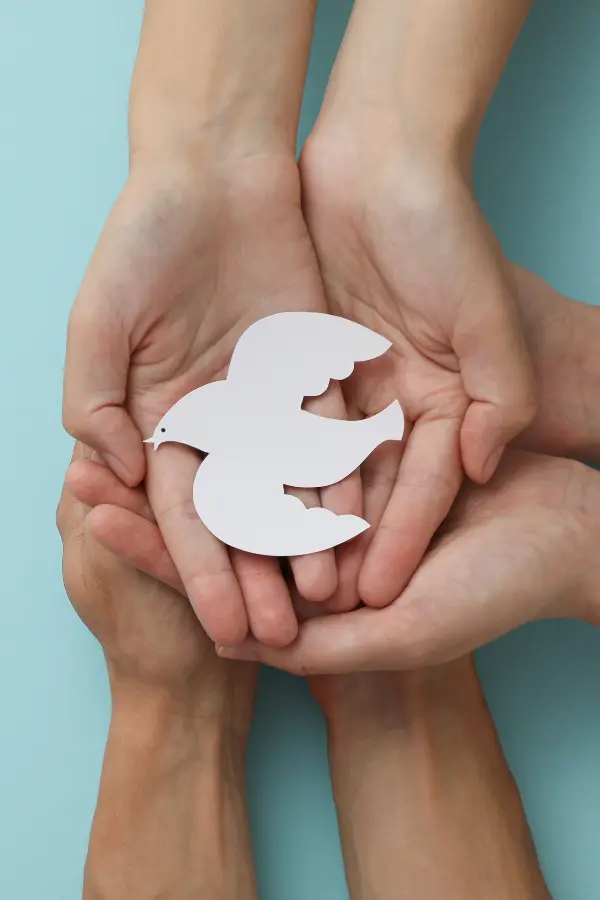 Three people holding a paper cut-out of a dove