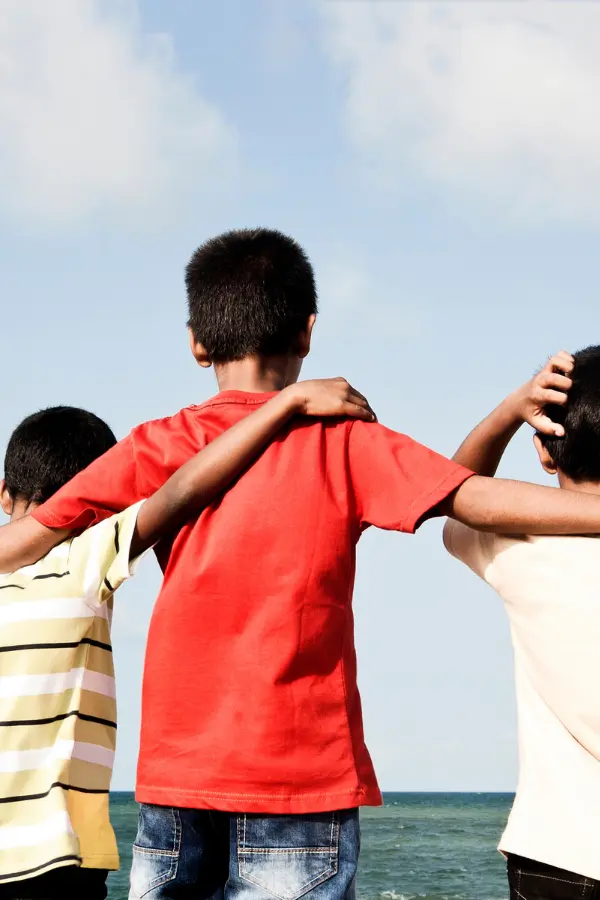 An older kid holding two younger kids
